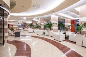 a lobby of a hospital with white chairs and plants at Konstantinos Palace in Karpathos