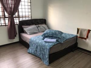 een slaapkamer met een bed met een deken erop bij Homestay Hani in Kuala Terengganu