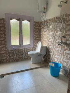 a bathroom with a toilet and a window and a bucket at KhenKhim Regency, Lachen all meals included in Lachen