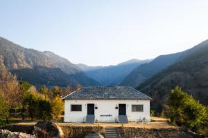 une maison blanche avec des montagnes en arrière-plan dans l'établissement Sukoon Baag, à Bir