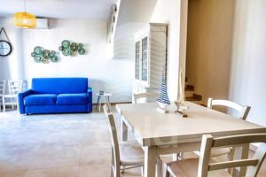 sala de estar con mesa y sofá azul en Villa Arya - Piscina privata, en Torre Lapillo