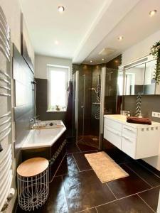 een badkamer met een bad, een wastafel en een douche bij App. Seyrl im Haus Karoline in Schladming