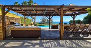 a wooden pergola with a table and chairs on a patio at Villa del Mar in Mazotos