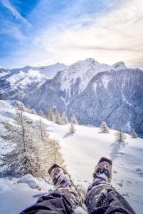 a persons legs in the snow on top of a mountain at "La Combe Fleurie" Appartements & Chambres in Saint-Bonnet-en-Champsaur