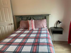 1 dormitorio con 1 cama con manta a cuadros y lámpara en Gestion clin d’oeil - 505, en La Tuque