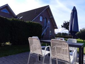 a table with four chairs and an umbrella at Helgas Ferienwohnung 4 Sterne in Südbrookmerland