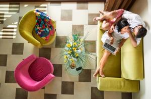 two people laying on a yellow chair with a laptop at Alexandra Golden Boutique Hotel-Adults Only in Chrysi Ammoudia