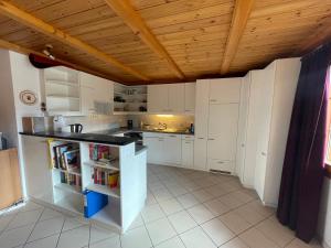 uma cozinha com armários brancos e um tecto de madeira em Gerendacherli 15 em Schwarzsee