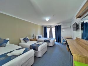 a hotel room with two beds and a desk at Albury Garden Court Motel in Albury