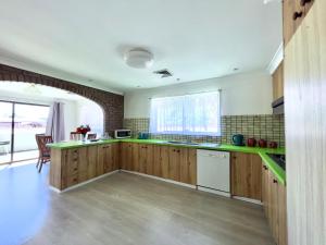 una cocina con armarios de madera y encimeras verdes en Albury Garden Court Motel, en Albury