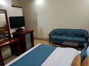 a living room with a blue couch and a television at HOTEL CORPORATE INN in Chandīgarh