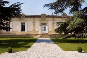 une vieille maison avec une porte blanche et quelques arbres dans l'établissement Château Fombrauge, à Saint-Christophe-des-Bardes