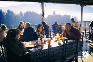 Eine Gruppe von Menschen, die an einem Tisch sitzen und Essen essen. in der Unterkunft Ash River Lodge in Clarens