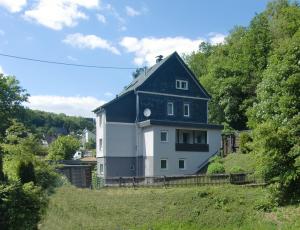 duży biały dom z czarnym dachem na wzgórzu w obiekcie Ferienwohnung Ilse und Eberhard Tröps w mieście Siegen