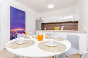 a white dining room with a white table and chairs at Apartments Villa Niko in Trogir