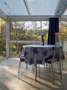 a dining room table with a wine bottle and two chairs at Horizons Verts Appartement Jasmin in Puivert