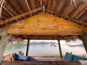 a roof of a hut over a body of water at La Rocha in Patnem