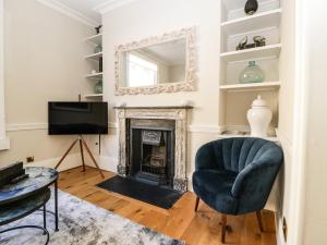 a living room with a fireplace and a chair and a mirror at 23 Daniel Street in Bath