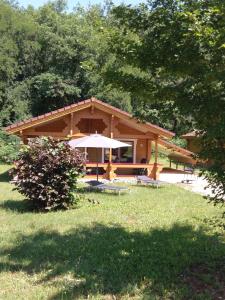 a house with an umbrella in a yard at "Au Cha les Vaux" Chalet 49 in Mauroux