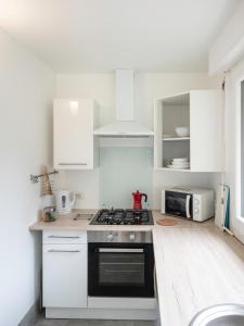 een keuken met witte kasten en een fornuis met oven bij Horizons Verts Appartement Cerisier in Puivert