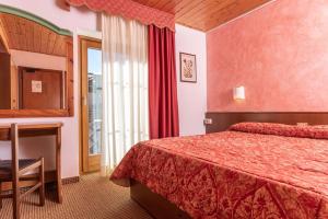a hotel room with a bed and a table and a window at Hotel Italo in Madonna di Campiglio