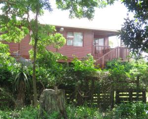 una casa roja con un porche y un árbol en Misty View Farm Stay en Towerhill