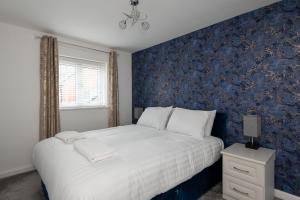 een slaapkamer met een bed met een blauwe muur bij Tudhoe View in Spennymoor