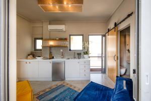 cocina con armarios blancos y sofá azul en Sunny Loft with Acropolis View, en Atenas