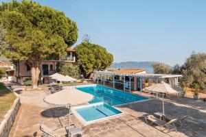 a swimming pool with umbrellas and a house at Hotel Ledra in Marathokampos