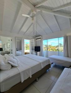a white bedroom with two beds and a ceiling fan at Pousada Solar da Ferradurinha in Búzios