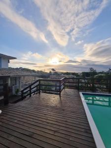 une terrasse en bois avec une piscine au-dessus d'une maison dans l'établissement Pousada Solar da Ferradurinha, à Búzios