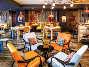 a restaurant with orange chairs and tables and tablesktop at ibis Styles Manchester Portland in Manchester