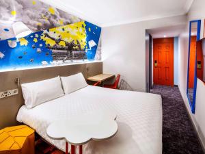 a bedroom with a white bed and a painting on the wall at ibis Styles Manchester Portland in Manchester