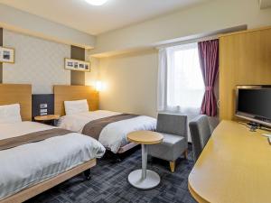 a hotel room with two beds and a tv at Comfort Hotel Suzuka in Suzuka