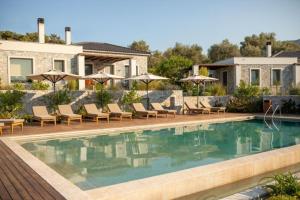 a villa with a swimming pool with chairs and umbrellas at Elies Residences in Mytilene