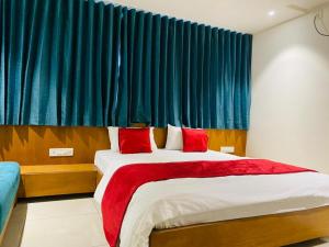 a bedroom with a large bed with red pillows at Hotel Prime in Gandhinagar