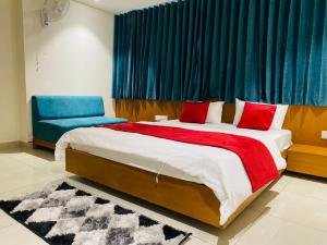 a bedroom with a large bed and a blue curtain at Hotel Prime in Gandhinagar