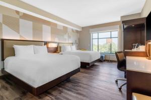 a hotel room with two beds and a desk at Cambria Hotel College Park in College Park