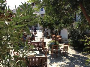 a patio with wooden chairs and tables and trees at Magnolia Apartment in Alonnisos
