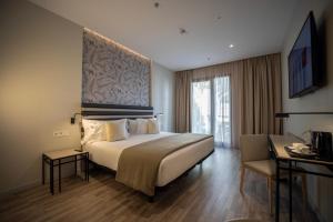 セビリアにあるabba Sevillaの大型ベッドとテレビが備わるホテルルームです。
