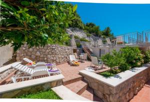 a patio with lounge chairs and a stone wall at Villa Borna Apartments in Dubrovnik