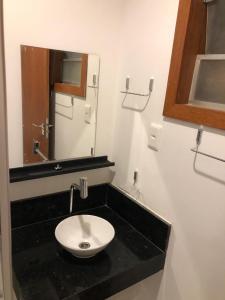 La salle de bains est pourvue d'un lavabo blanc et d'un miroir. dans l'établissement Casa, 2 Suítes com Ar, Piscina a 400 mts Praia - Taipu de Fora, Barra Grande #4, à Marau