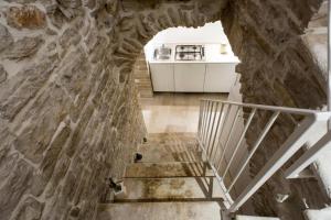 una escalera en una casa de piedra con paredes y cocina en LE SUITES AL TORRIONE, en Ruvo di Puglia