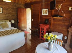 ein Schlafzimmer mit einem Bett und einer Vase aus Blumen auf einem Tisch in der Unterkunft Pousada Mon Desir in Penedo