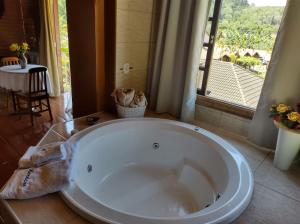 baño con una gran bañera blanca y ventana en Pousada Mon Desir, en Penedo