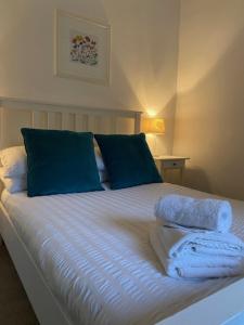 Una cama con almohadas azules y toallas. en Self-contained luxurious feel apartment, en Dunfermline