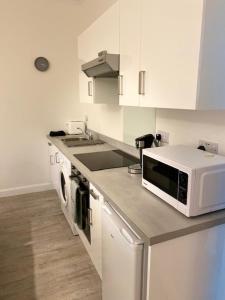 a white kitchen with a microwave and a sink at Self-contained luxurious feel apartment in Dunfermline