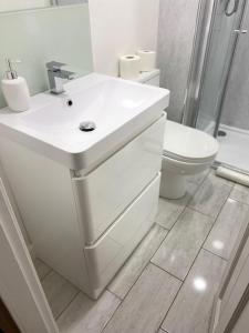 La salle de bains blanche est pourvue d'un lavabo et de toilettes. dans l'établissement Self-contained luxurious feel apartment, à Dunfermline