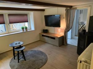 a living room with a flat screen tv and a stool at Hexenhäuschen Wankendorf in Wankendorf