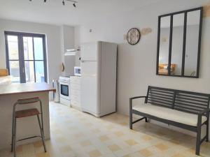 eine Küche mit einem Kühlschrank, einer Bank und einem Tisch in der Unterkunft Appartement au coeur du village- Ref12 in Saint-Paul-Trois-Châteaux